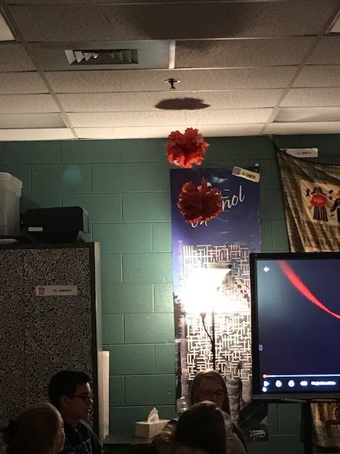 At the bottom of the picture next to the girl with glasses head, on the left side you see this strange light which could possible be a spirit trying to manifest. The next photo was taken a second later and now the light object is close to the ceiling on the left of the flower hanging from the ceiling.