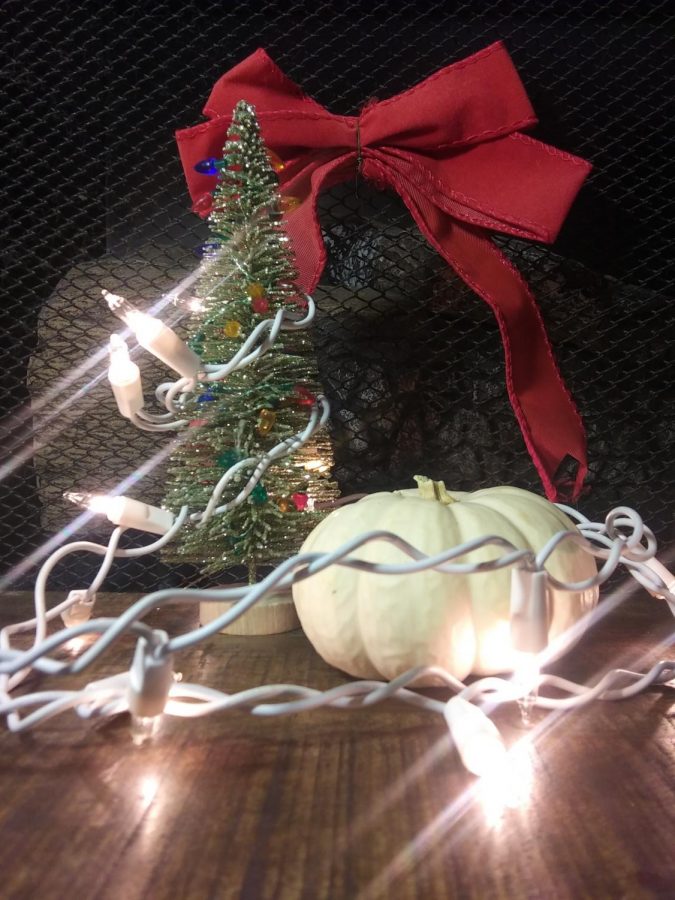 Holiday lights wrapped around a pumpkin and a mini Christmas tree