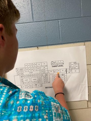 Freshman student at Lafayette looking at a map in a hallway during class change.