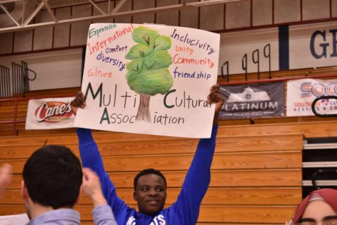 [Lexington, KY] Multi-Cultural Association, International Tutoring, and Multicultural Fair member Tapiwanashe Kunaka holds a sign at 8th Grade Night to get future freshmen interested in the clubs.