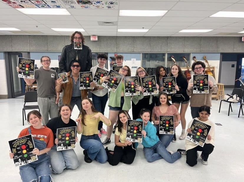 Image of last years Advanced Theatre 3 class holding posters for their One Stoplight Town show. Taken on 4/11/23