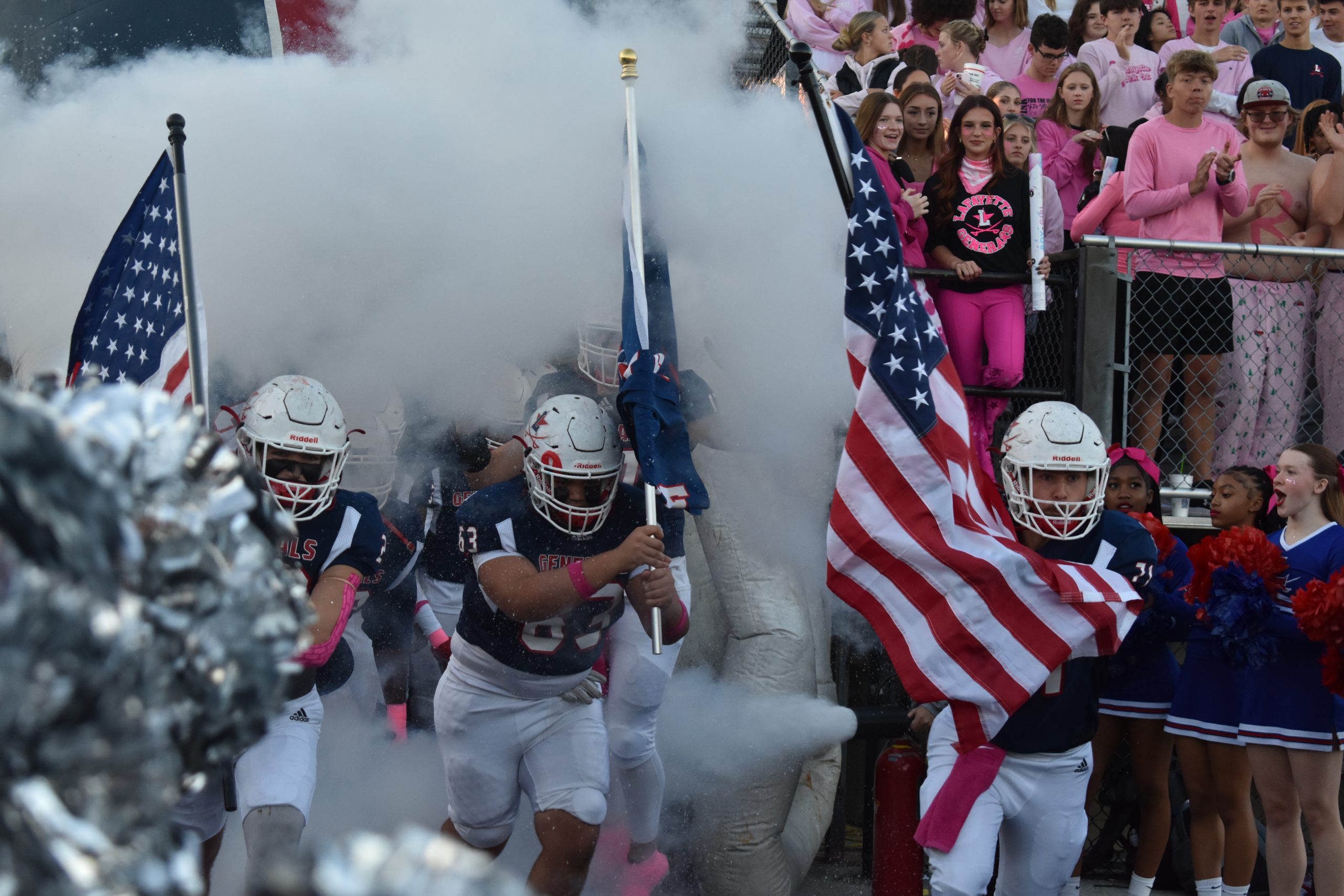 Lafayette football team starts their game fueled by high energy. Hudson Moore (#71) Noah Leon (#63) and Matthew Hardin( #23) run out waving The American flag and Lafayette's flag. Friday, Oct. 18th. 6:22 pm.