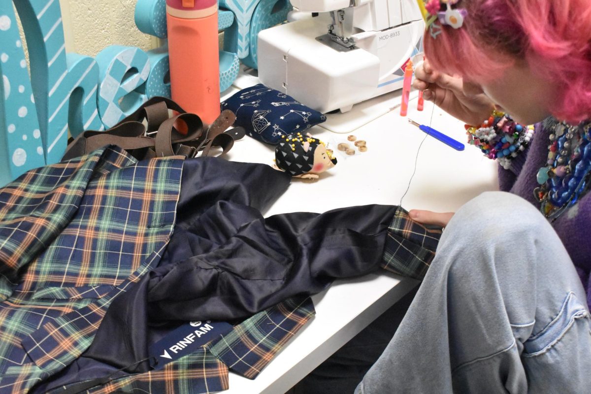 Costume crew member Izzy Brewer hemming the sleeves of a costume on Thursday, Jan. 15, 2025. Before the show, the costume crew makes adjustments to the costumes, like hemming, pressing, and finalizing small details.
